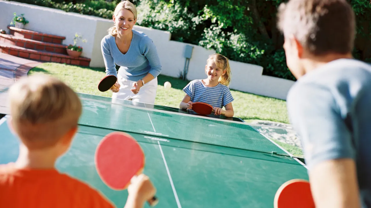 Family playing table tennis at Hungry Hollow's outdoor play zone in Austin